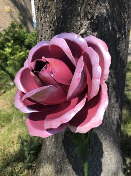 Een kunstwerkje, grote roze roos gemaakt van metaal, op steel