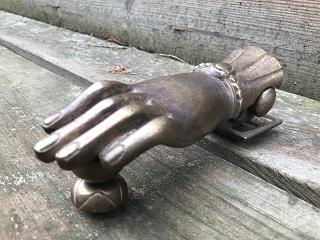 Grote deurklopper in de vorm van een hand, van zwaar messing